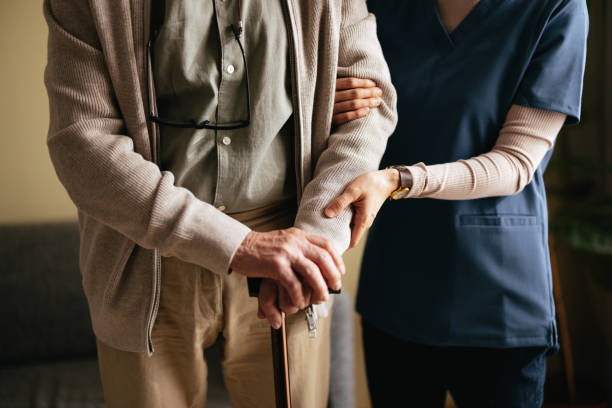 Caregiver providing gentle support to elderly person with cane