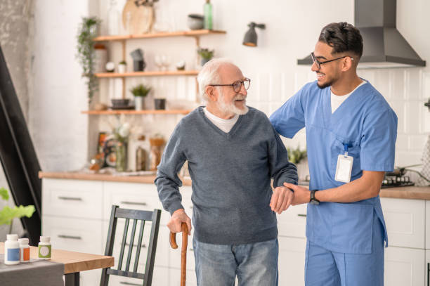 Male nurse assisting elderly client in home kitchen